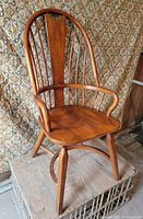 Three-quarter view of full chair showing wood finish and spindle back