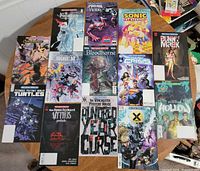 All 13 comics laid out on round table, front covers visible