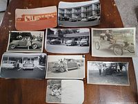 All nine photographs spread on table showing various scenes with antique cars