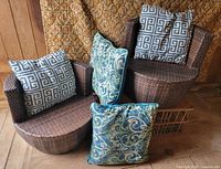 Two wicker chairs with four pillows displayed