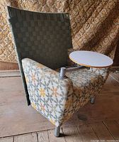 front angled view showing patterned upholstery, woven back, tablet arm stowed