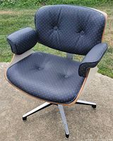 Three-quarter view of chair showing upholstery, wood trim and metal base