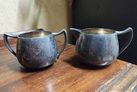 Front view of creamer and sugar bowl showing form and tarnish