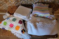 Four folded textiles on bench showing colours, patterns, fringe