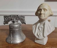 Liberty Bell coin bank beside Washington bust bottle