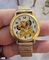 Front view showing Simba dial and gold-tone stretch band