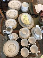 View of the full china set with all different types of dishes arranged on a glass surface.