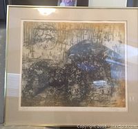 Framed print showing two women embraced with signature and numbering visible on the artwork.