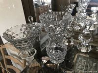 Display of two pedestal crystal bowls with heavy geometric cuts, one with a club-shaped finial on lid.