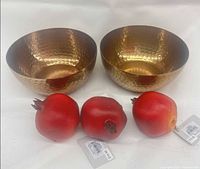 Two hammered brass bowls and three resin pomegranates displayed