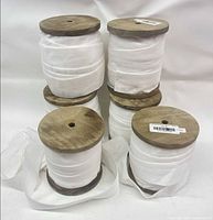 Six wooden spools of white velvet ribbon stacked, full view