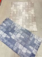 Both grey and blue vinyl tile rugs laid flat showing patterns and sizes