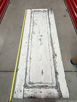 Unrolled Beija Flor vinyl sheet showing distressed wood panel design with tape measure for scale
