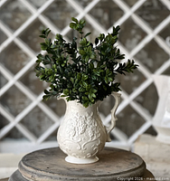 Artificial boxwood stems displayed in a decorative pitcher