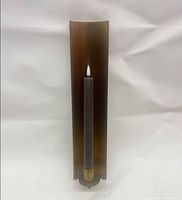 Full view of brass wall sconce with taper candle inserted