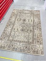 Full view of rectangular wool oriental rug showing overall pattern and size reference tape