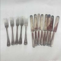 Group view of five forks and nine knives showing overall quantity and style