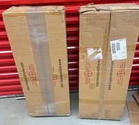 Two sealed cardboard cartons labeled Koppers Home leaning against red door