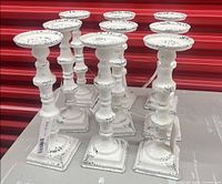 group of nine matching distressed white metal candlesticks on table