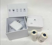 Printer, two extra label rolls, open box with power adapter and cable