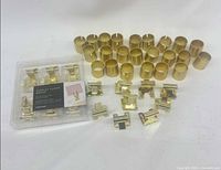 Overall lot showing sealed clamp set, loose clamps and numerous brass cylindrical holders