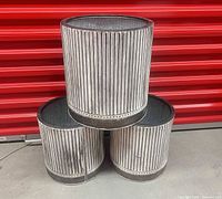Three cylindrical metal planters stacked showing striped exterior finish