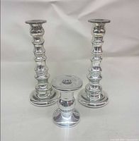 Group shot of all three silver candle holders, showing size difference