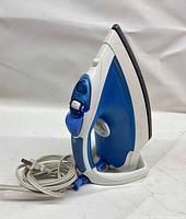 Full side view of blue/white T-fal iron standing upright showing soleplate edge and cord