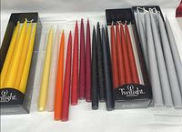 Assorted coloured taper candles in boxes and tray