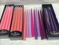 Assorted pink, coral, lavender, fuchsia and purple Twilight taper candles in boxes and trays