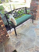 Full view of black metal bench on patio showing seat and back design