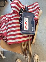 Box containing multiple small U.S. flags on wooden poles