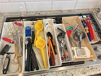 All five organizer trays filled with assorted stainless, plastic and silicone kitchen utensils