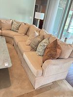 Full view of curved beige fabric sectional with pillows