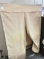 Full view of beige fabric portable wardrobe with curtain closed, showing wheels