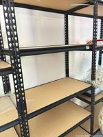 Full view of assembled shelving unit showing steel frame and four particleboard shelves