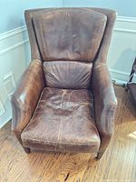 Front view of brown leather armchair showing overall design and wear