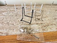 Group of mixed acrylic and metal easel stands plus bag of additional hardware