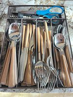Tray showing wood-look handle flatware, corkscrew, blue kitchen shears