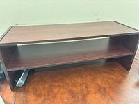 front view of dark brown monitor riser showing open shelf