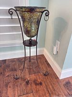 Full view of crackle glass vase seated in metal stand