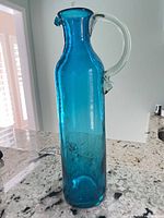 Full view of teal hand-blown glass pitcher showing color, height and clear handle