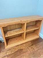 Front view showing overall structure, four open shelves, light oak finish