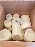 Mixed pillar and round ivory LED candles inside cardboard box