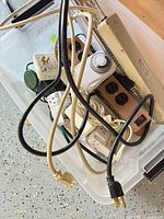 Open plastic bin showing timers, power strips, adapters and cords