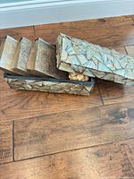 Shell-clad box with lid and faux book ornament displayed on hardwood floor