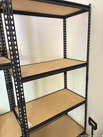 Full view of shelving unit showing metal frame and three of four particleboard shelves