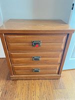 Front view showing three drawers and hardware