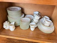 Stacked dinner plates, salad/dessert plates, saucers, teacups, creamer and sugar bowl