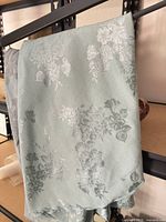 Full view of folded seafoam green damask tablecloth/runner on shelf